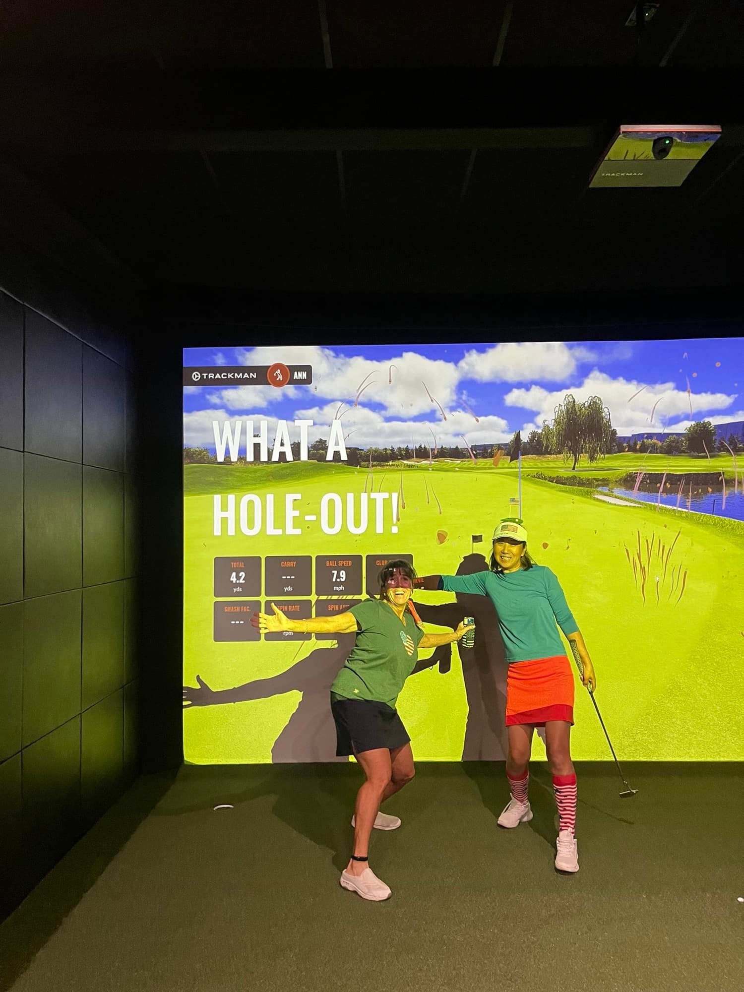 Two friends celebrating a hole-out on the simulator at Unbound Golf